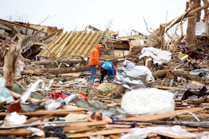 Deux hommes fouillent les débris après une tornade.