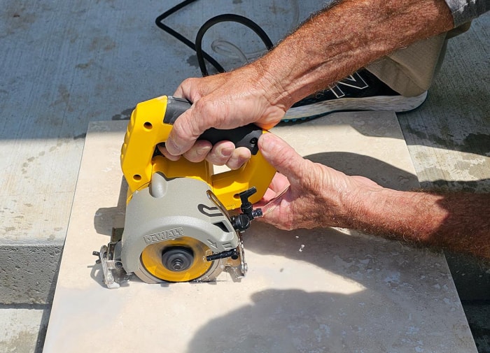 Une personne utilise une version manuelle de la meilleure scie à carreaux pour couper un grand carreau.