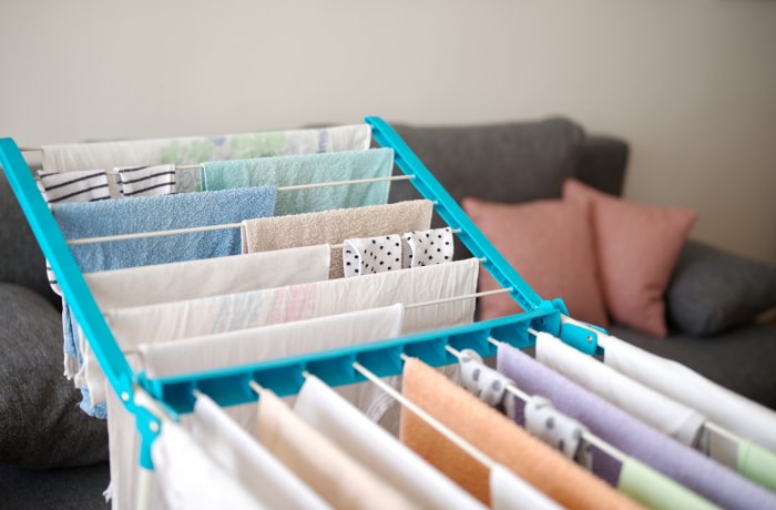 linge séchant sur un étendoir à linge dans le salon avec un canapé en arrière-plan