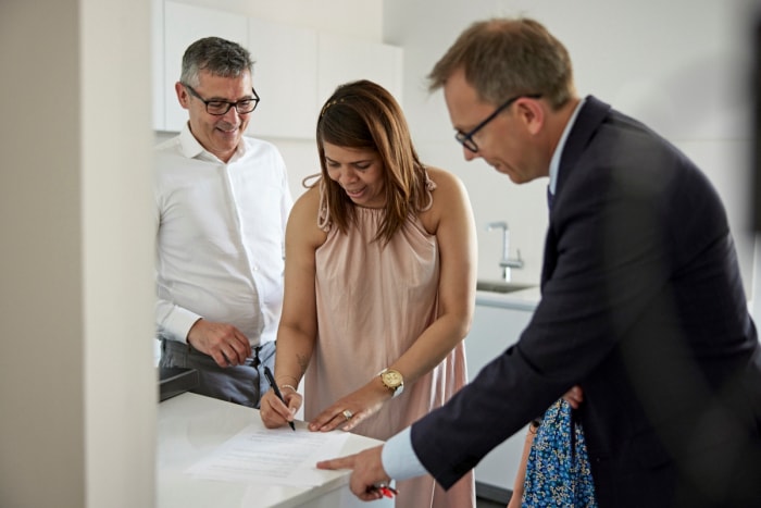 Un couple âgé signe un document avec un agent masculin