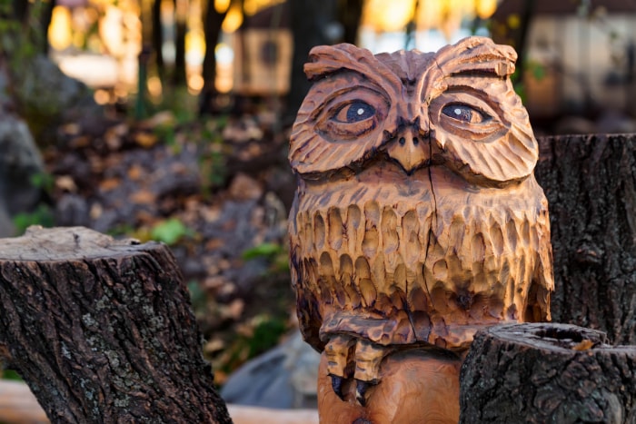 Sculpture décorative de hibou en bois dans une cour.