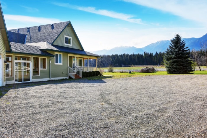 Une maison à la montagne dispose d'une grande allée de gravier devant.