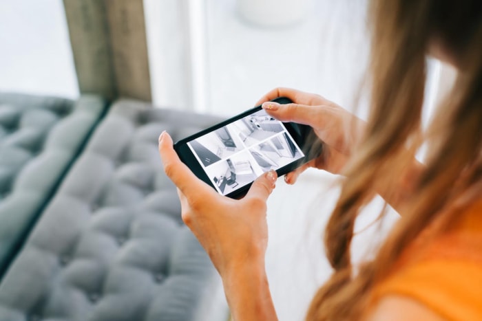 Une femme regarde l'écran de son téléphone et regarde les images de la caméra de sécurité.