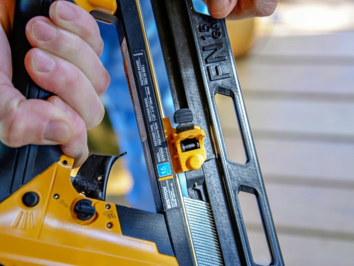 Personne utilisant une cloueuse de finition sur des planches de plancher