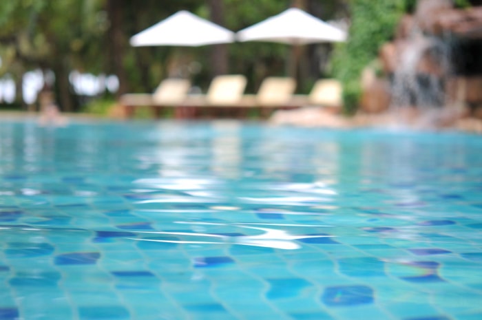 Une piscine étincelante avec des chaises longues et des parasols en arrière-plan.