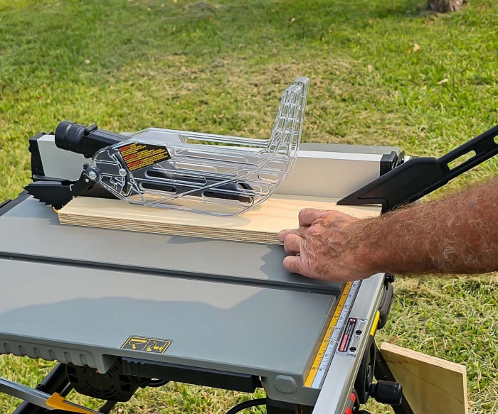 Une personne utilisant la scie à table DeWalt de 10 pouces pour couper un morceau de bois