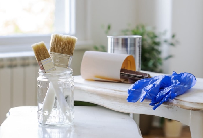 Un groupe d'outils de peinture de meubles sur une petite table prête à être peinte.