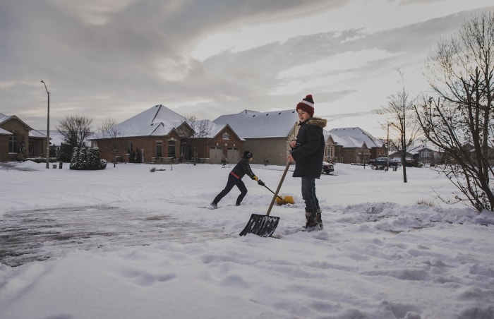 Deux frères pelletent l'allée après une légère chute de neige.