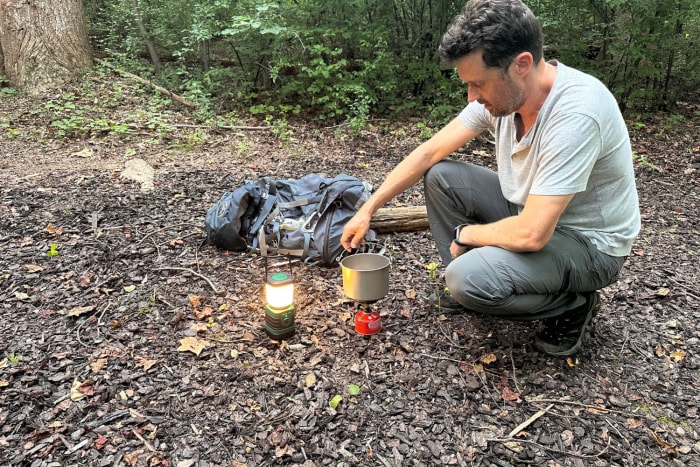 Une personne utilise la lumière de la lanterne LED Lepro pour voir où allumer un réchaud de camping