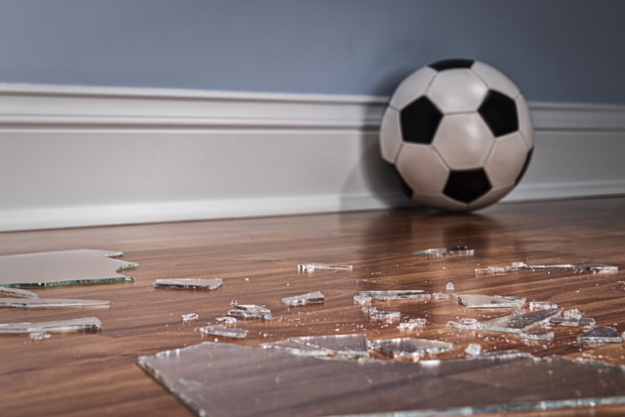 film de sécurité pour fenêtre ballon de football sur plancher en bois avec vitre cassée