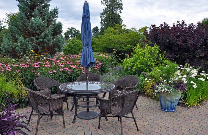 terrasse de jardin avec table et quatre chaises de jardin et parasol