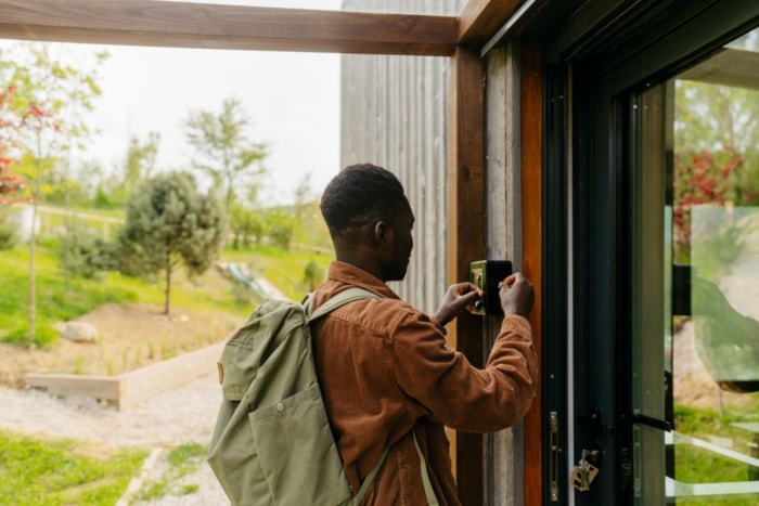 Une personne reçoit une clé dans une boîte avant de franchir la porte d'entrée d'une maison. 