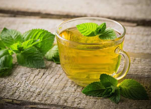 Tasse transparente de thé à la menthe avec une feuille de menthe sur le dessus