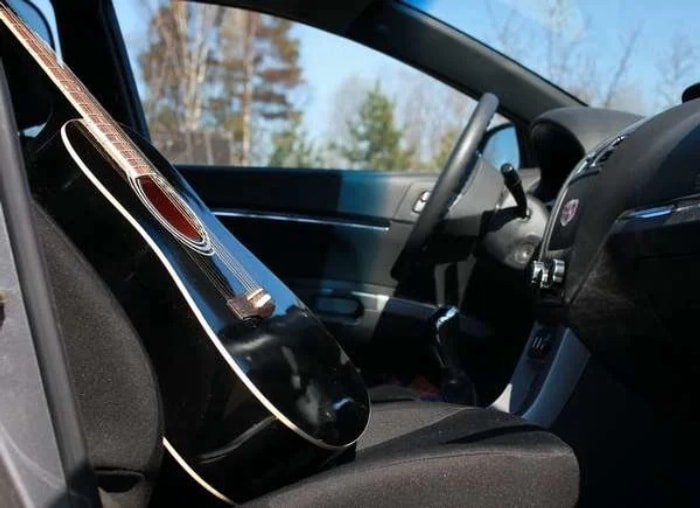 Guitare acoustique noire sur le siège avant de la voiture