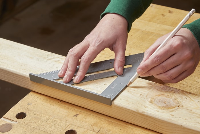 Femme mesurant une planche avant d'effectuer une coupe transversale à l'aide d'une scie circulaire.