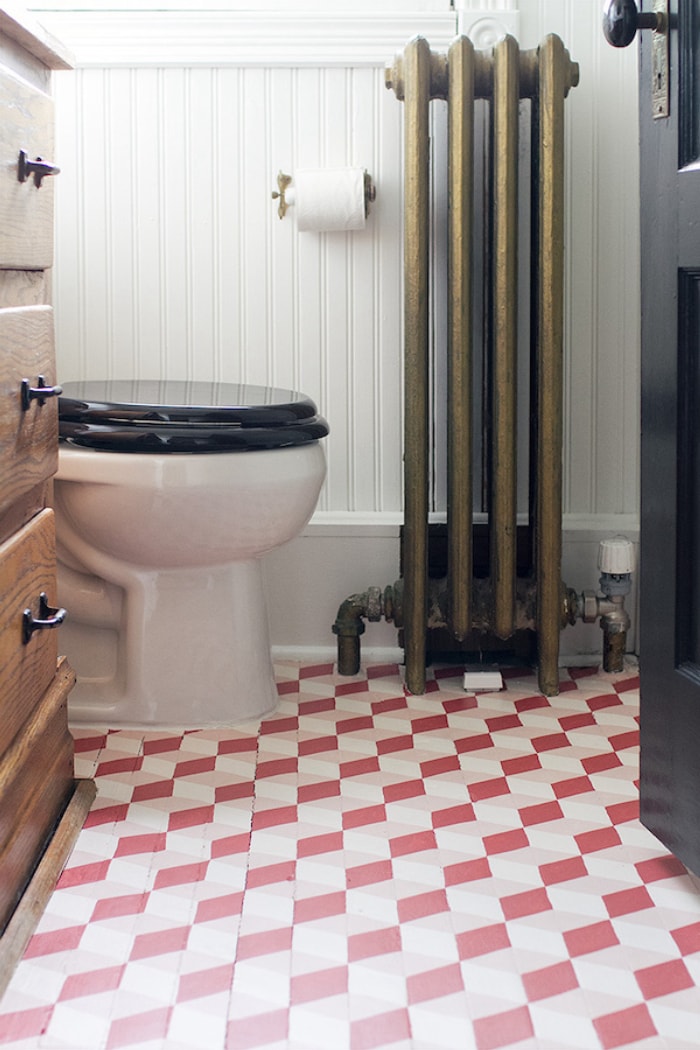 Salle de bain vintage avec radiateur et sol en carrelage peint avec un motif de dés en cascade rose.