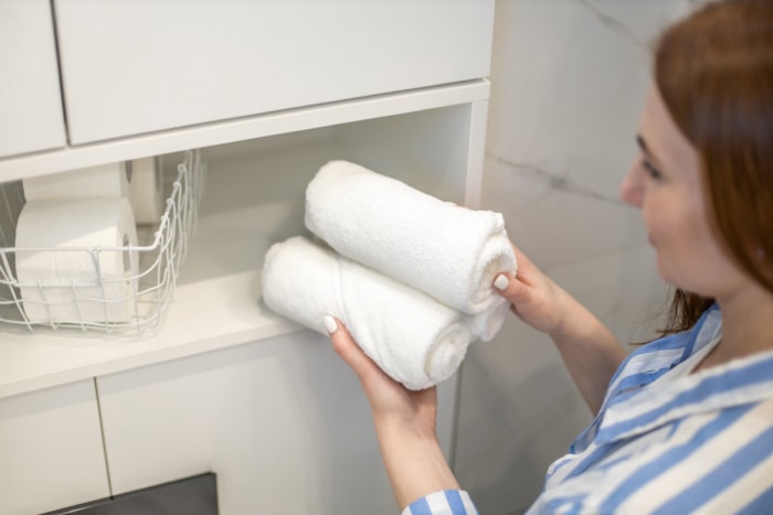 Femme mettant des serviettes dans la salle de bain.