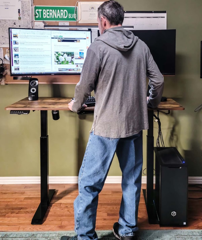 Un homme se tient debout et travaille sur un ordinateur au bureau debout de Fezibo