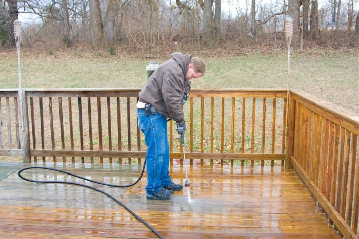 Une personne lave une terrasse sous pression.