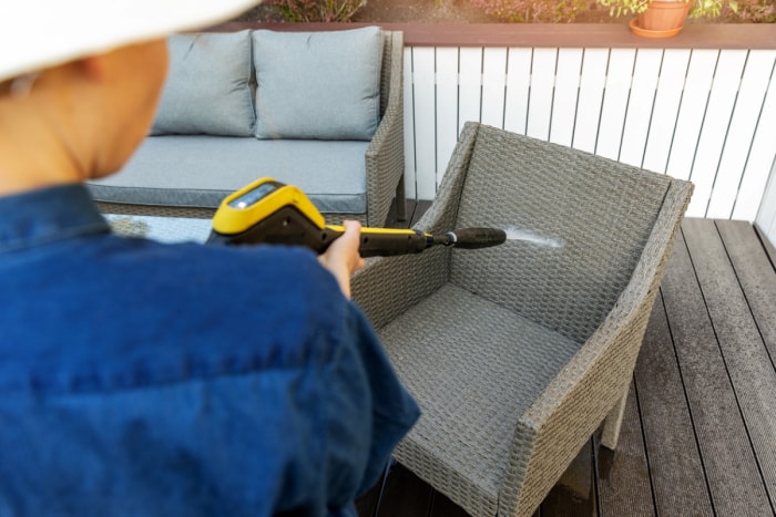 Personne utilisant un nettoyeur haute pression sur des meubles de jardin