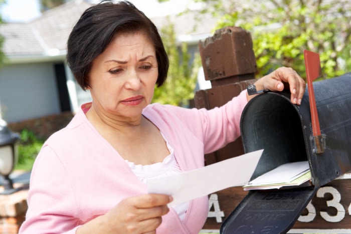 vol de titre de propriété - femme âgée fronçant les sourcils devant le courrier