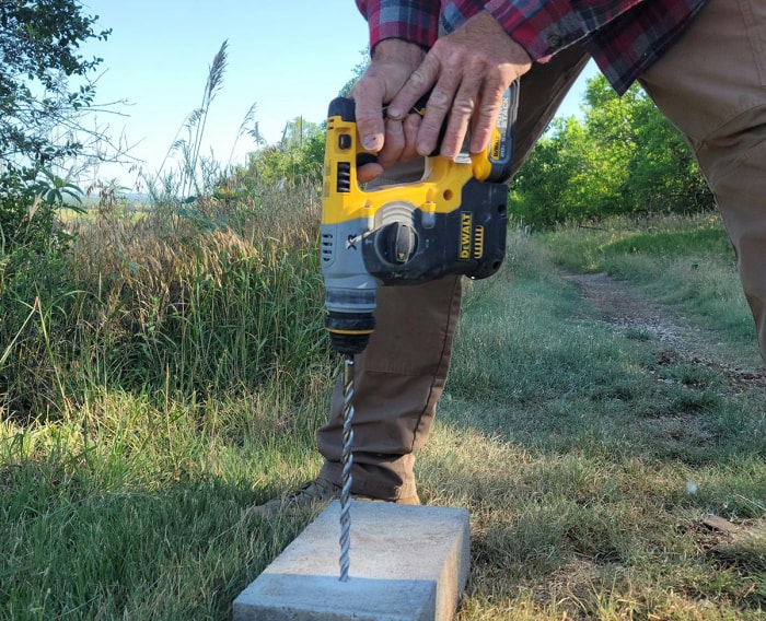 Une personne utilisant une perceuse à béton DeWalt alimentée par une batterie PowerStack DeWalt