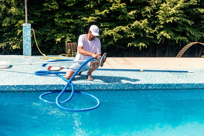 Un homme utilise un outil pour nettoyer une piscine.