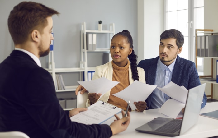 iStock-1329553958 couple héritant d'une maison se réunit avec un avocat tout en examinant des documents