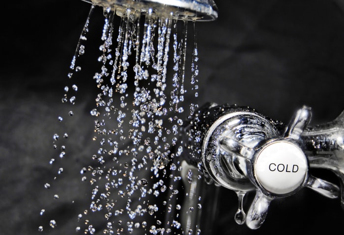 Robinet de bain chromé et eau qui coule de la pomme de douche