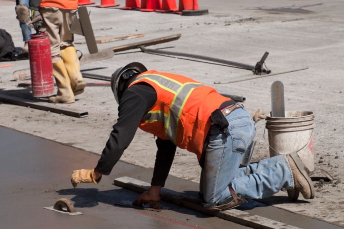 Un ouvrier nivelle le béton d'une allée.