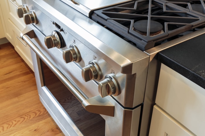 Gros plan d'une cuisinière à gaz en acier inoxydable avec des grilles en fer noir