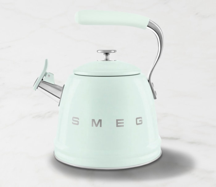 Une bouilloire à thé Smeg vert menthe se trouve sur un fond blanc.