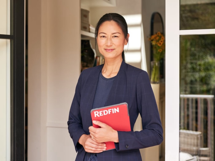 Agent immobilier asiatique tenant une tablette rouge Redfin