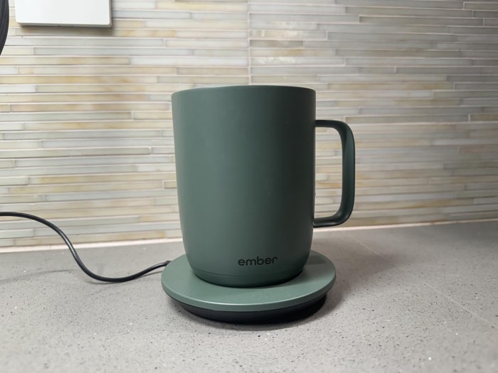 La tasse Ember 2 en vert sauge sur un comptoir de cuisine sur son sous-verre de chargement branché. La tasse Ember 2 en vert sauge sur un comptoir de cuisine sur son sous-verre de chargement branché. La tasse Ember 2 en vert sauge sur un comptoir de cuisine sur son sous-verre de chargement branché.