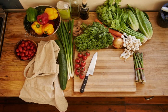 Une variété de légumes frais repose sur un bloc de boucherie fraîchement scellé dans une cuisine. 