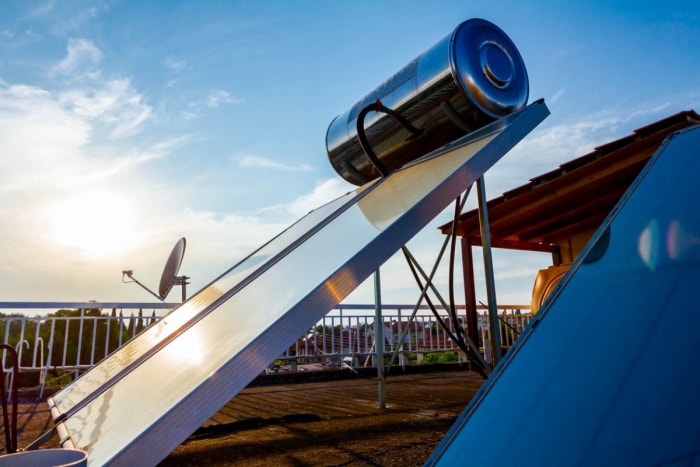 Un chauffe-piscine solaire sur un toit avec une antenne parabolique en arrière-plan.