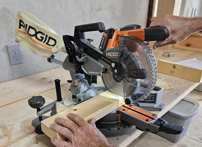 Un entrepreneur utilise une scie à onglet Ridgid de 7 1/4 pouces pour couper un 2 par 4.