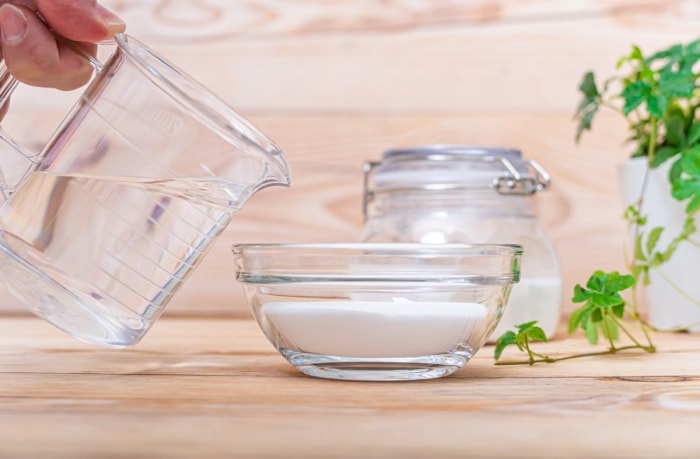 Verser l'eau du gobelet gradué dans un petit bol avec le bicarbonate de soude.