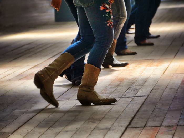 groupe-avec-des-jeans-et-des-bottes-de-cowboy-dansant-en-ligne-sur-un-plancher-en-bois