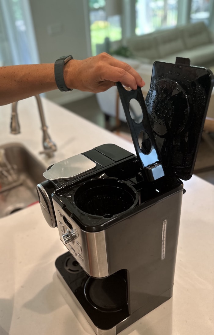 Un homme retire le filtre à charbon de la cafetière Cuisinart