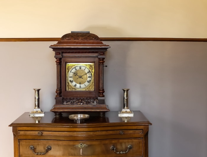 Horloge de cheminée ancienne avec rangement à sa base.