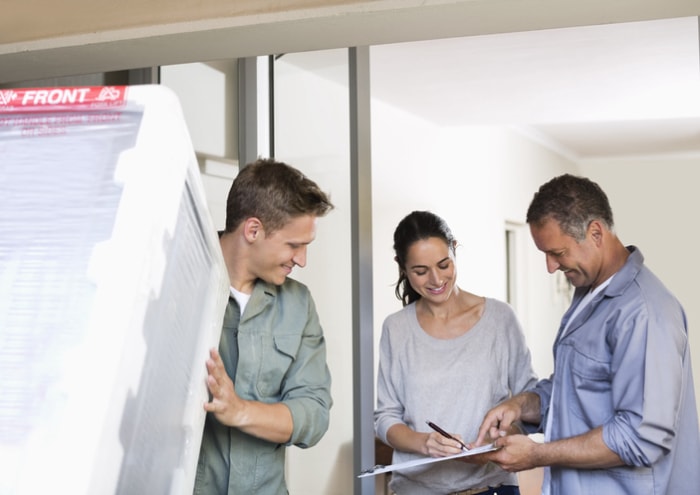 une femme signe pour un nouvel appareil électroménager avec deux ouvriers pour un crédit d'impôt pour l'efficacité énergétique