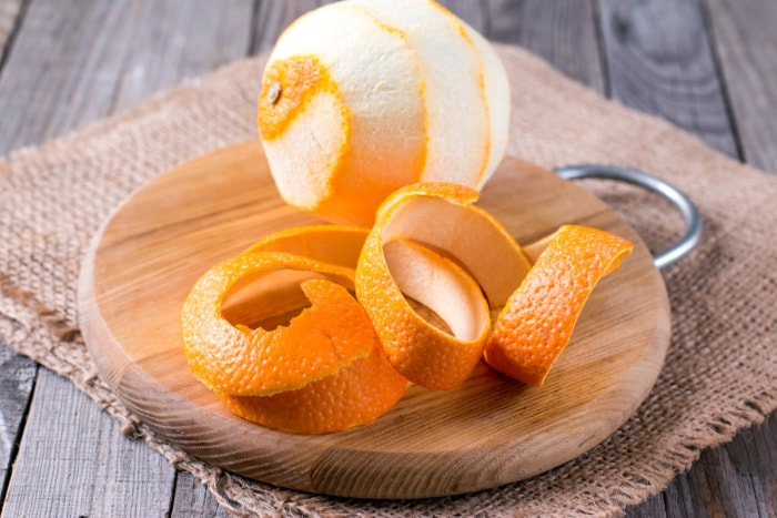 Une orange épluchée sur une assiette en bois.