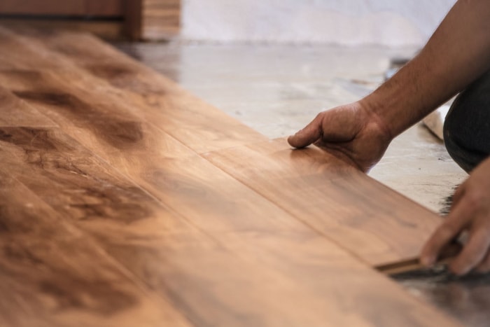 Mains d'un homme montrant comment installer un parquet en bois massif