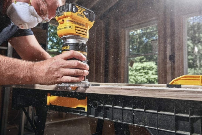 Une personne utilisant la meilleure toupie à bois pour débutants pour fraiser le bord d'une planche.