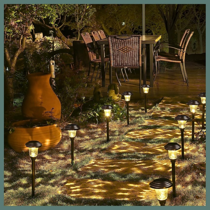 patio arrière avec allée en pierre éclairée par de petites lumières menant à une table et des chaises