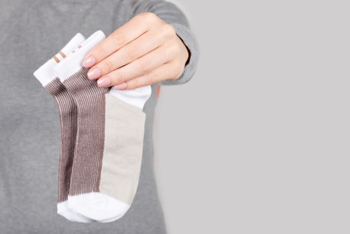 moyens de nettoyer derrière et sous chaque appareil - femme tenant une paire de chaussettes