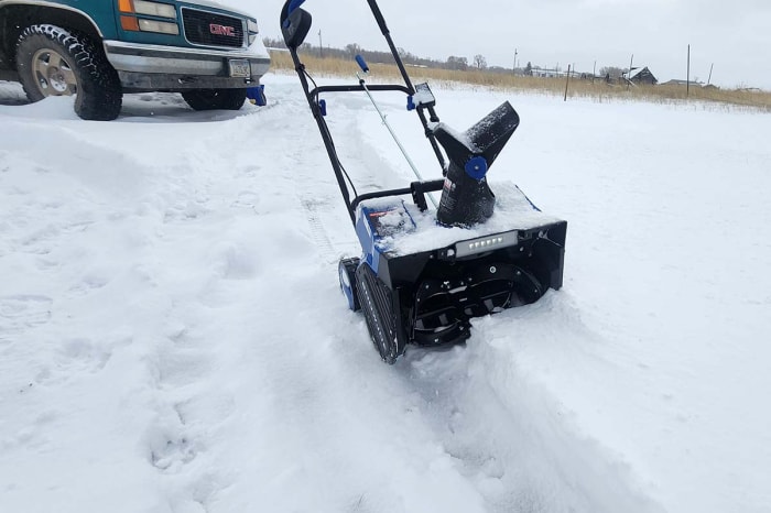 La souffleuse à neige mono-étage Snow Joe sur une grande dalle de ciment recouverte de neige pendant les tests.