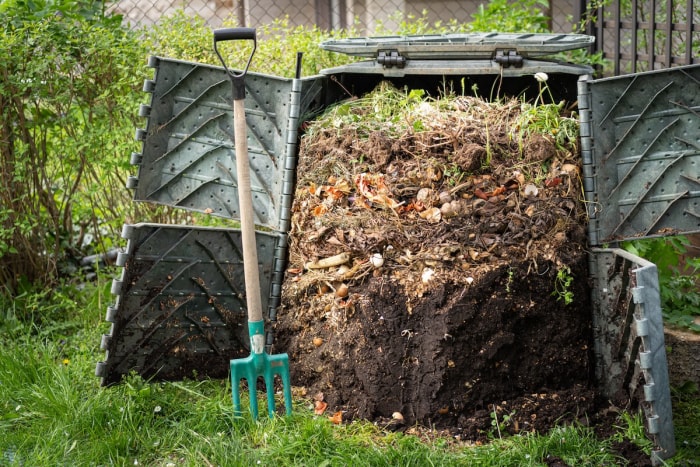 Un grand bac à compost dans une cour résidentielle produisant de l'humus pour la pelouse et le jardin.