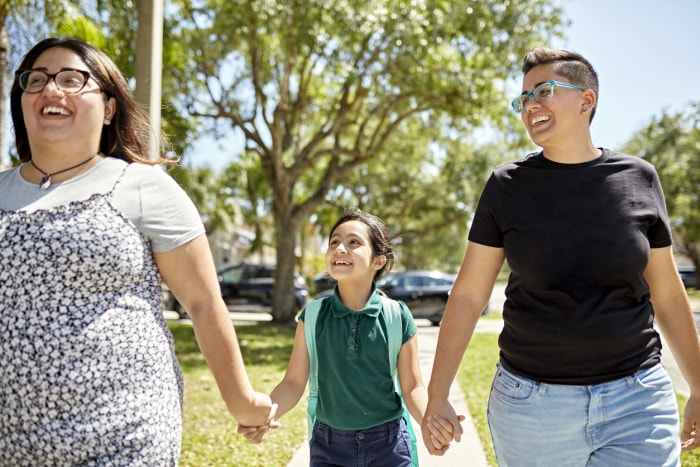 iStock-1411828603 communauté planifiée de grande envergure Famille LGBTQIA souriante se rendant à l'école à pied